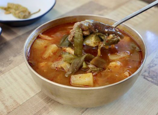 숟가락으로 뜬 소고기와 대파 — 놋그릇에 담은 소고기국밥