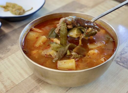 숟가락으로 뜬 소고기와 대파 — 놋그릇에 담은 소고기국밥